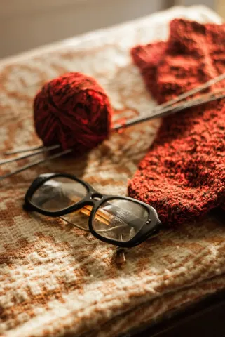 Ball of wool, needles and black eye glasses.  Photo by Coman Alex on Unsplash